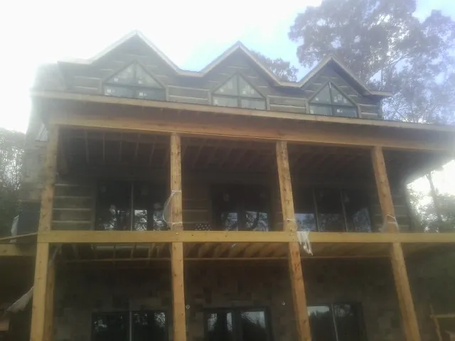 Dormers and porch framing on a large log home under construction — Roof Coating work by our crew in Madera